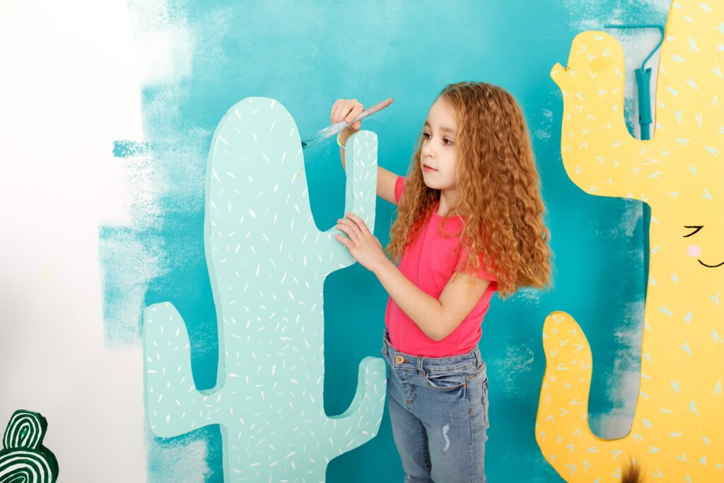 Girl painting a cactus with a brush indoors