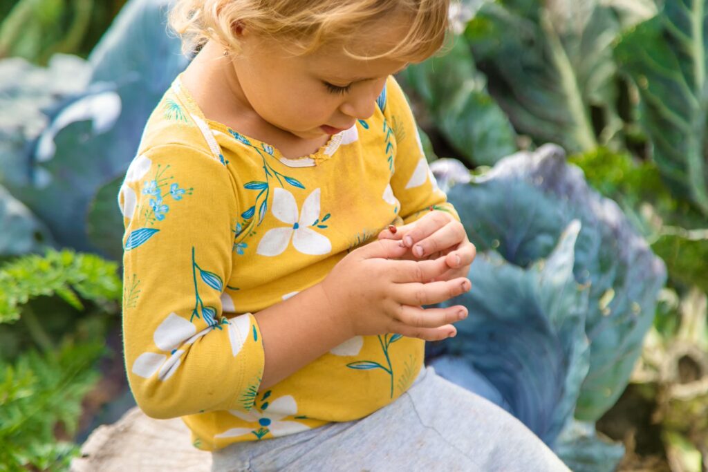 Toddler examining a ladybug in a lush green garden